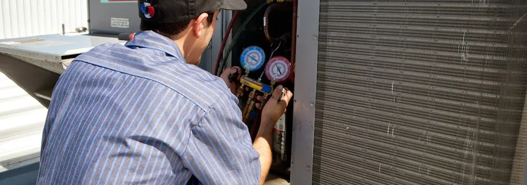 HVAC technician servicing a condenser unit in Denison