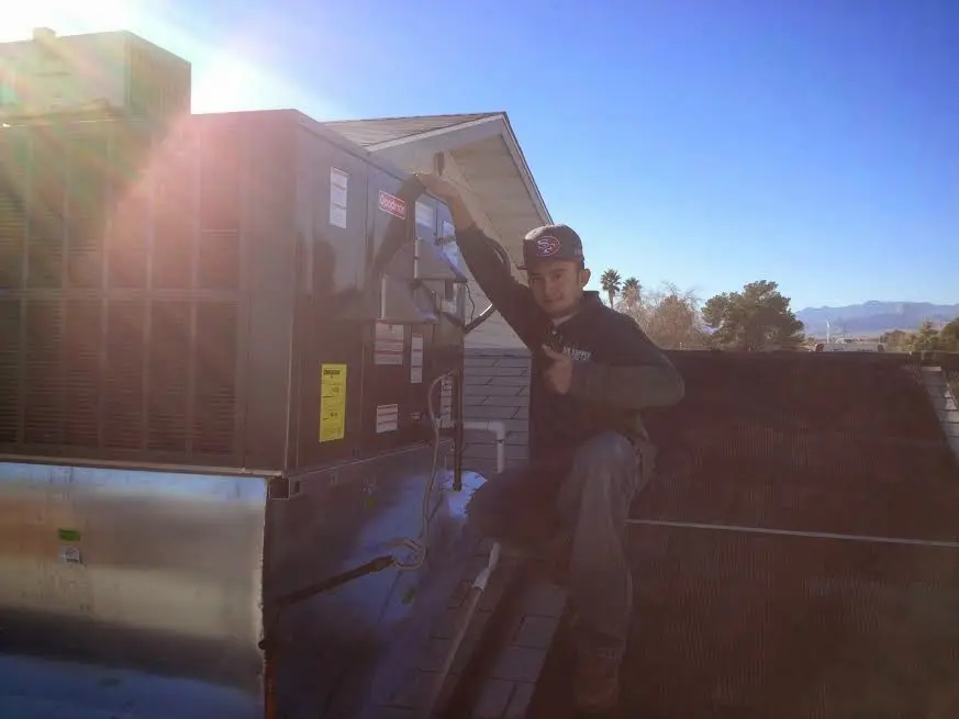HVAC technician performing AC Tune-Up on a rooftop unit in Denison